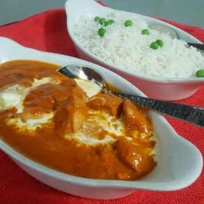 A tasty dish of curry with rice and peas served in two bowls.